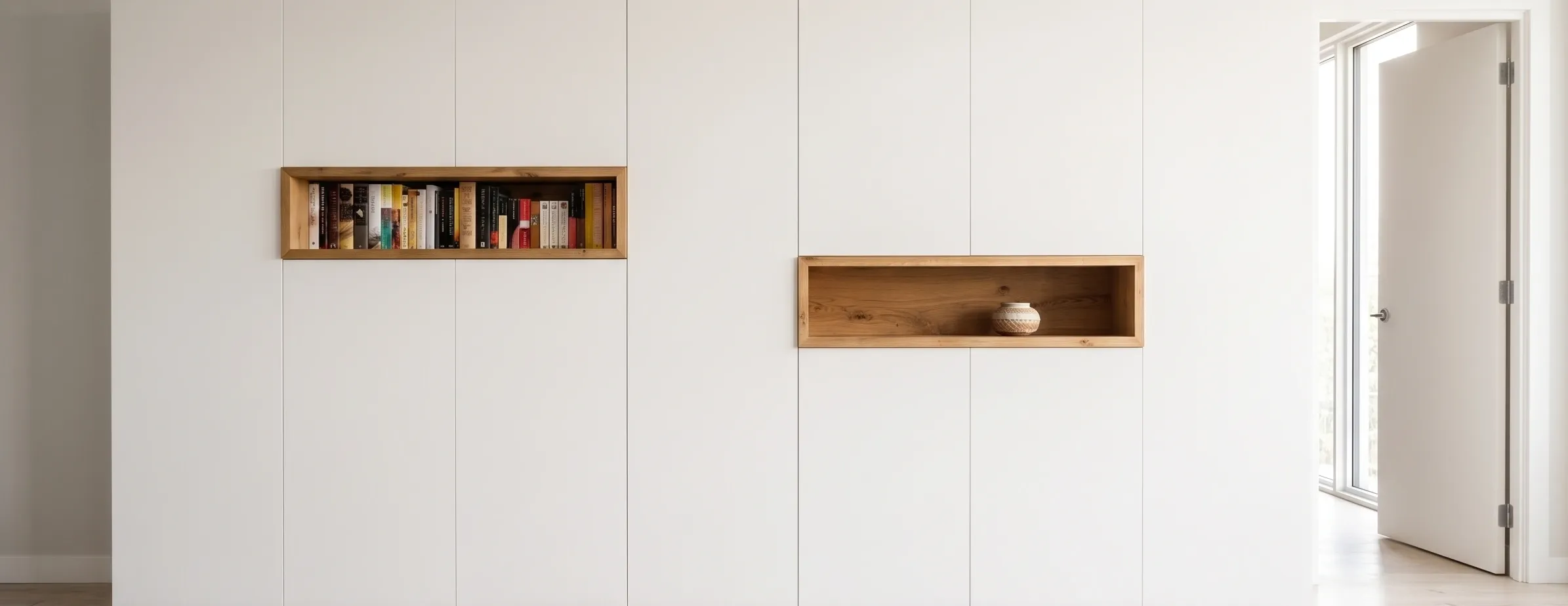 Frente de armario empotrado blanco mate con nichos decorativos en madera de roble para libros, diseño de interiores minimalista.
