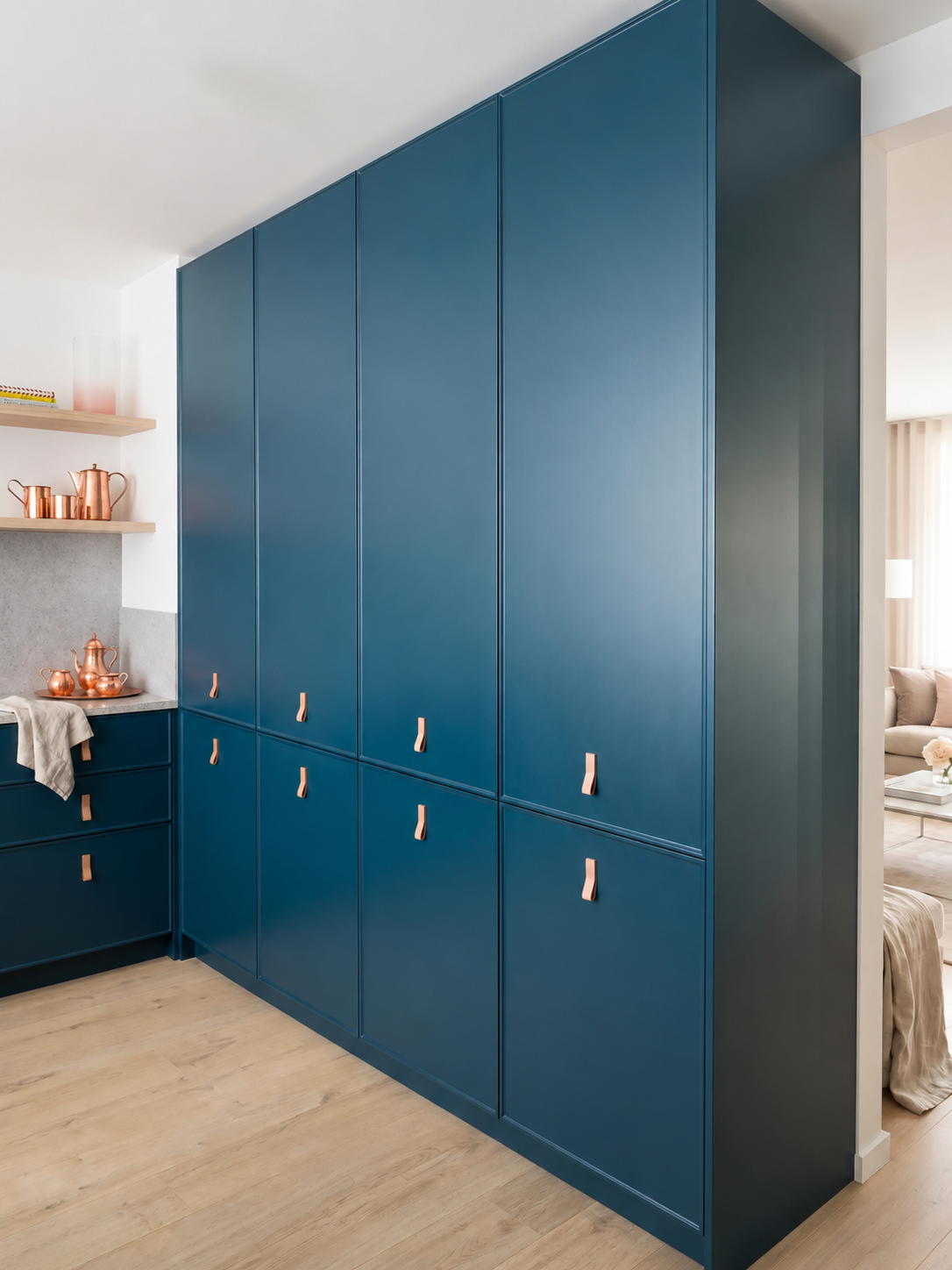 Mobiliario de almacenaje a medida en color azul petróleo con tiradores de cuero natural y detalles de cobre en cocina moderna.