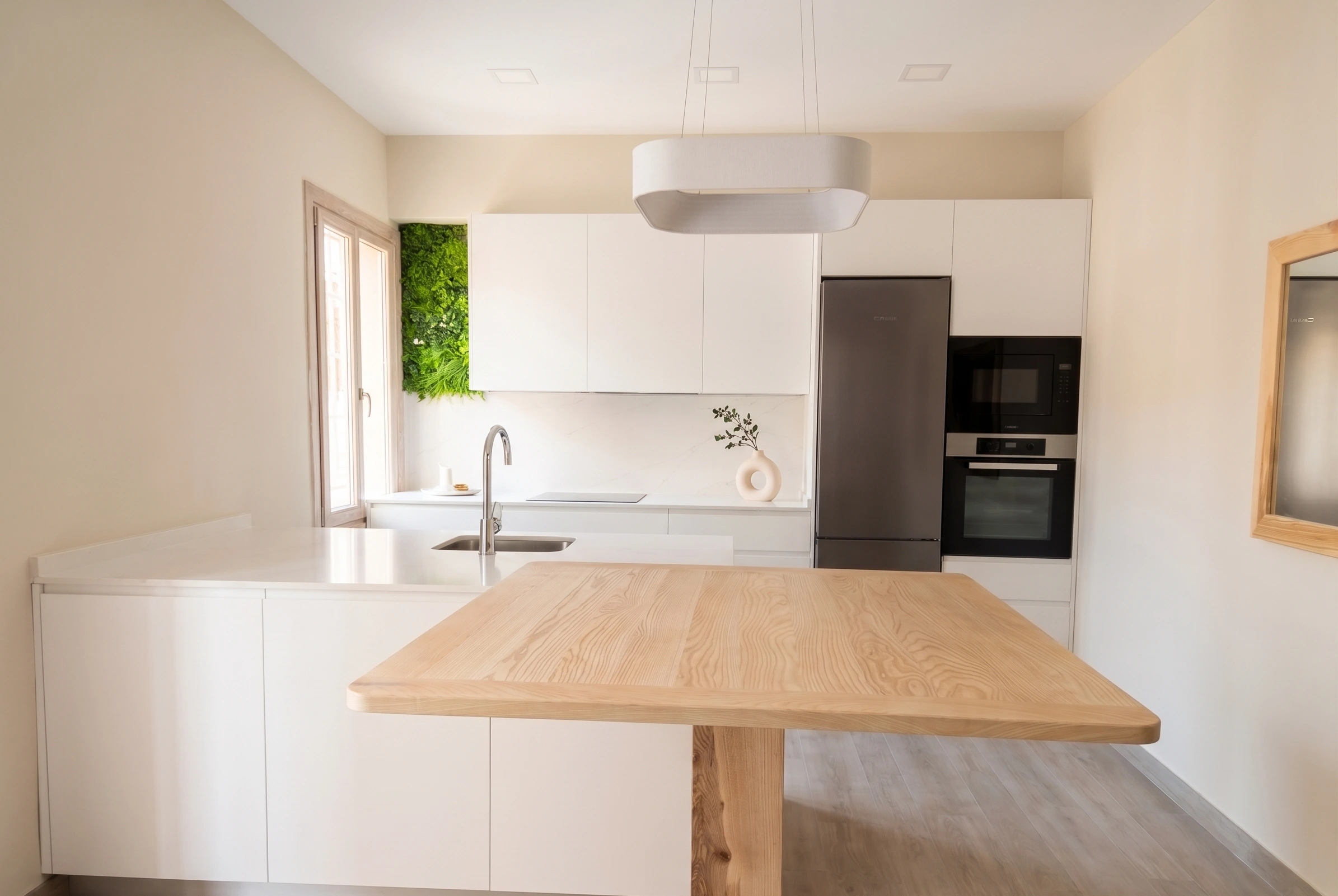Diseño de cocina minimalista con muebles blancos, barra de madera y jardín vertical en la pared