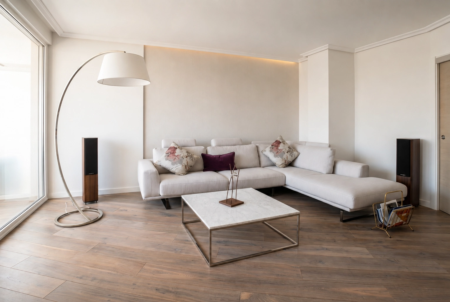 Diseño de interiores y decoración de salón luminoso con mesa de mármol, lámpara de pie de arco y altavoces integrados.