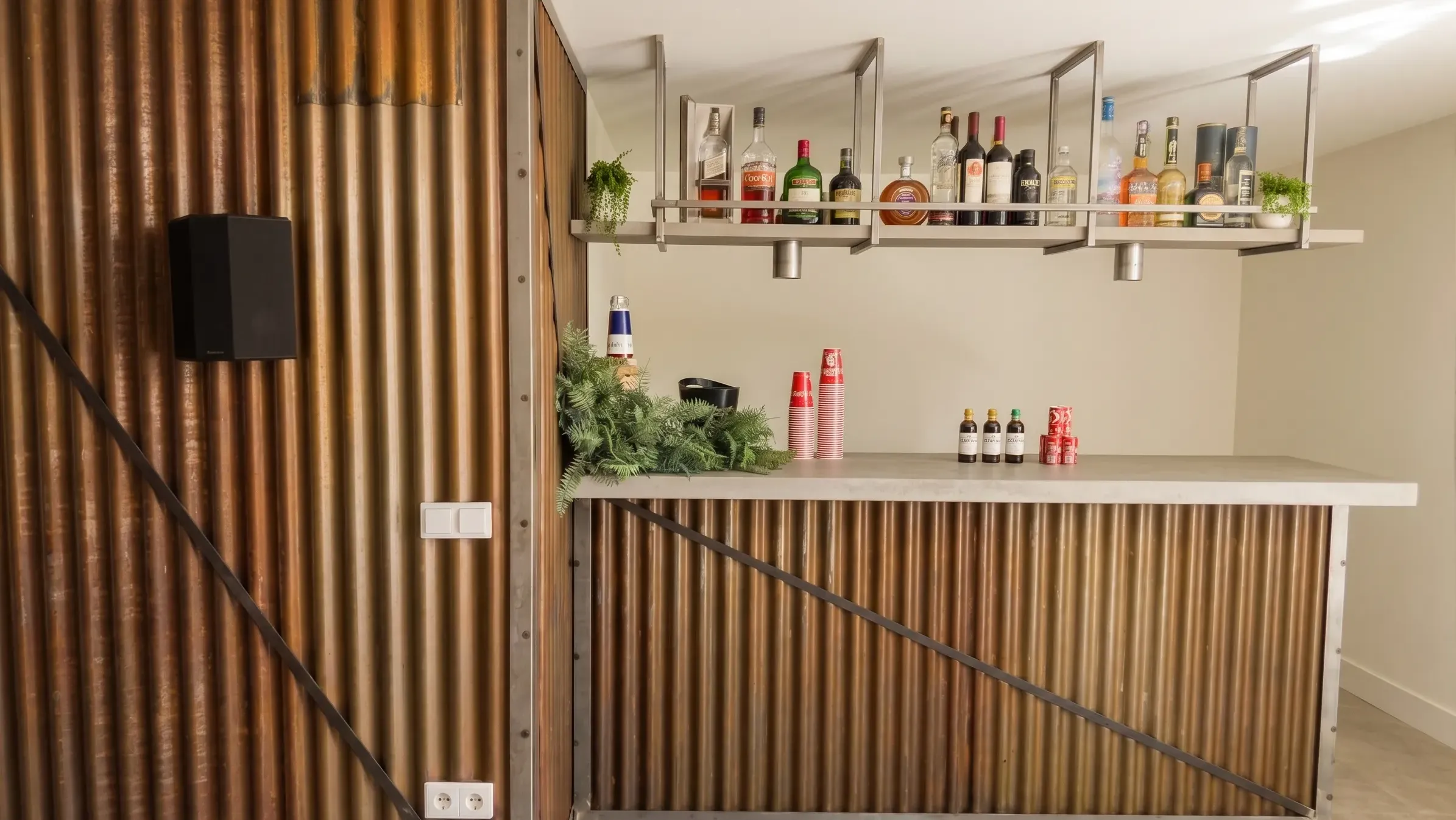 Diseño de barra de bar con chapa ondulada efecto óxido y estantería metálica suspendida en reforma de sótano moderno.