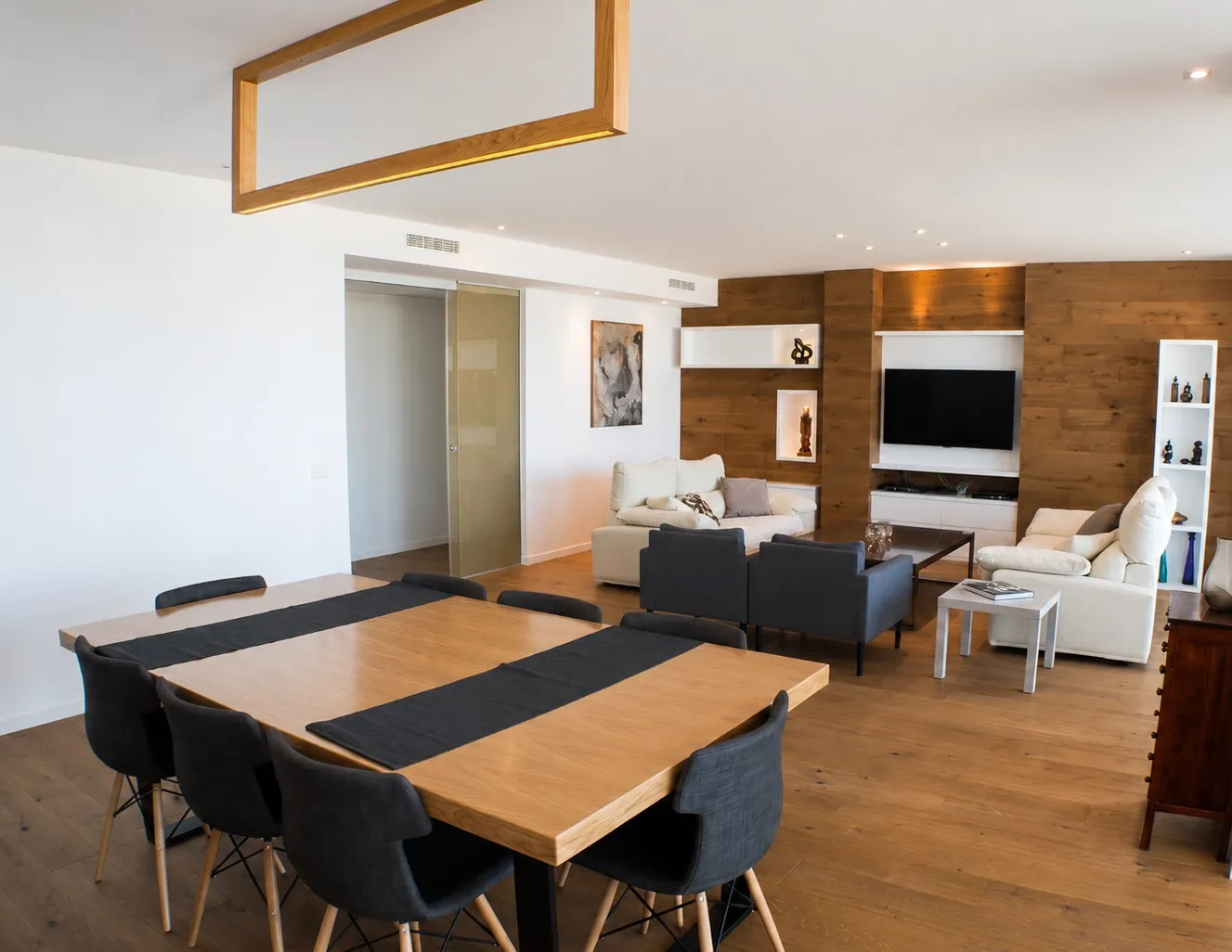 Reforma integral de salón comedor moderno con suelo de parquet y pared revestida de madera en Madrid
