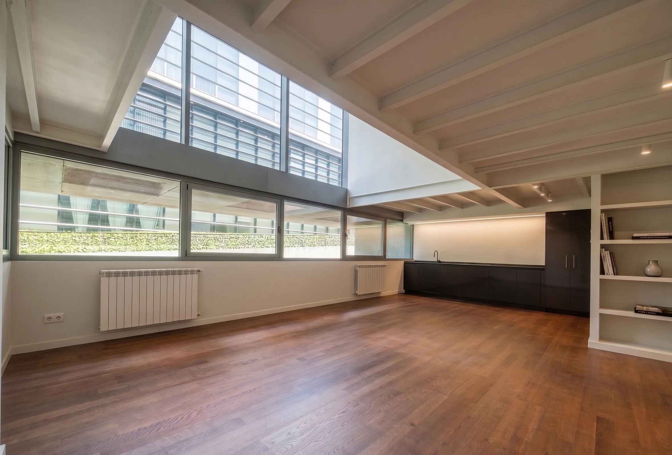Diseño de interiores y reforma de un espacio tipo loft con vigas vistas y suelo de parqué en Madrid.